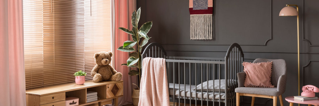 Sweet, pastel pink accessories in a classic, dark nursery bedroom interior with wooden furniture and a gray crib for a child