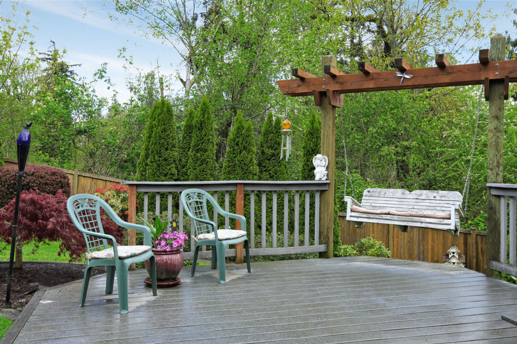 Cozy wooden deck with two old chairs and garden swing